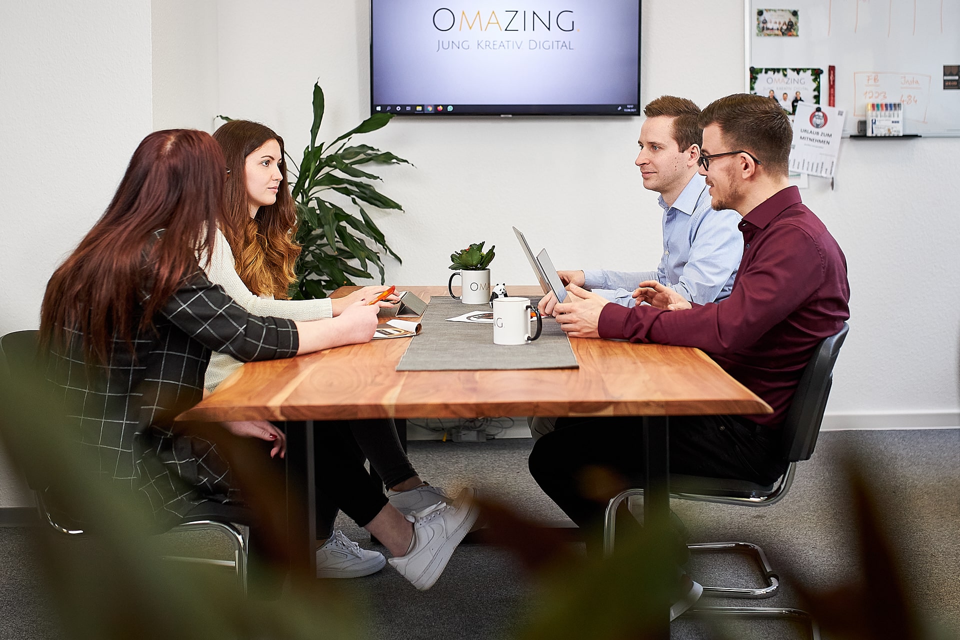 Am Tisch sitzen vier Personen, die über ein Projekt im Online-Marketing-Bereich reden.