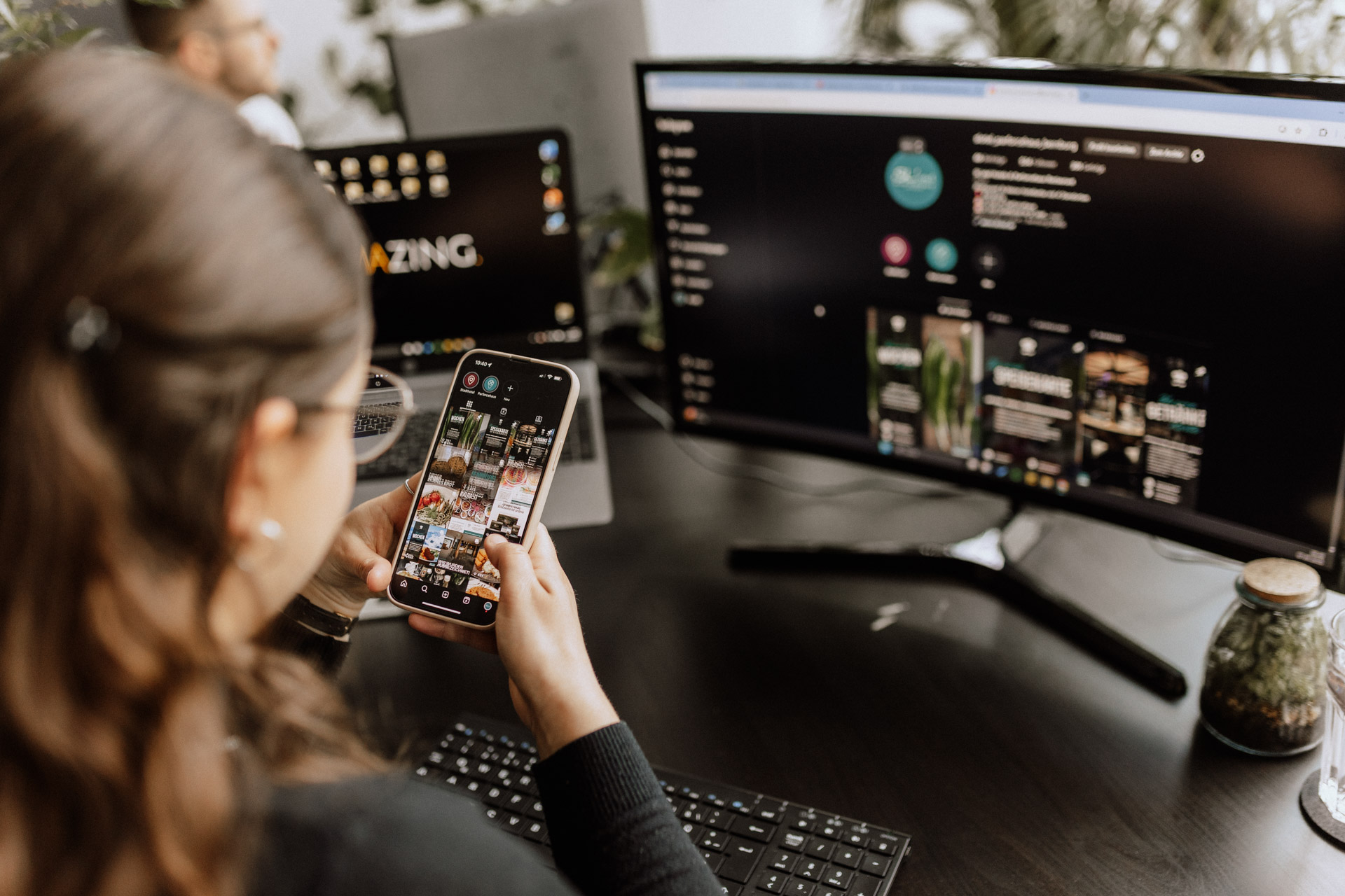 Mitarbeiterin am Smartphone und Arbeitsplatz von Omazing